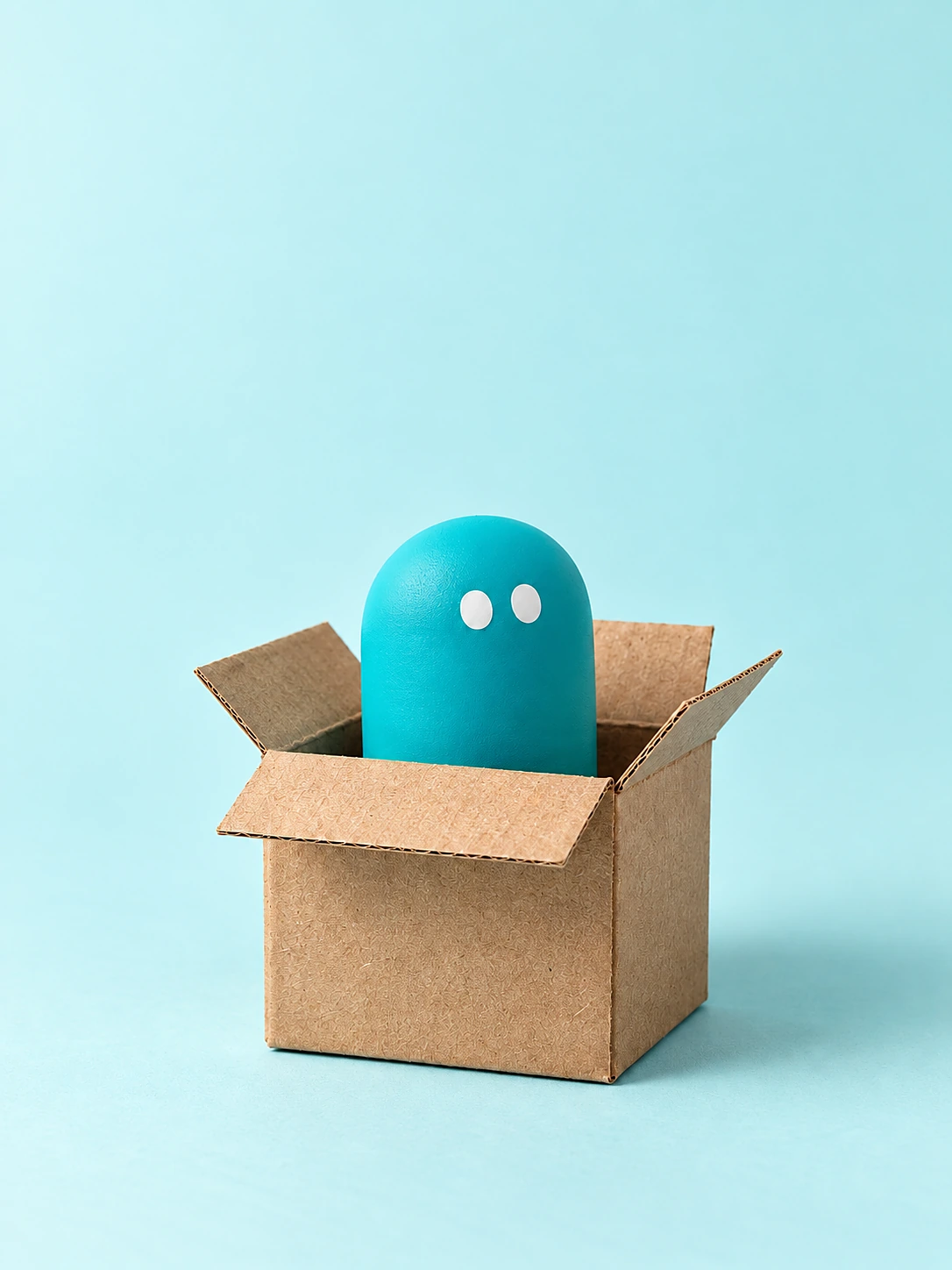 A teal pill peeking out of a cardboard box.